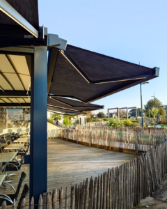 Store banne sur une pergola bioclimatique pour une terrasse de restaurant de bord de mer