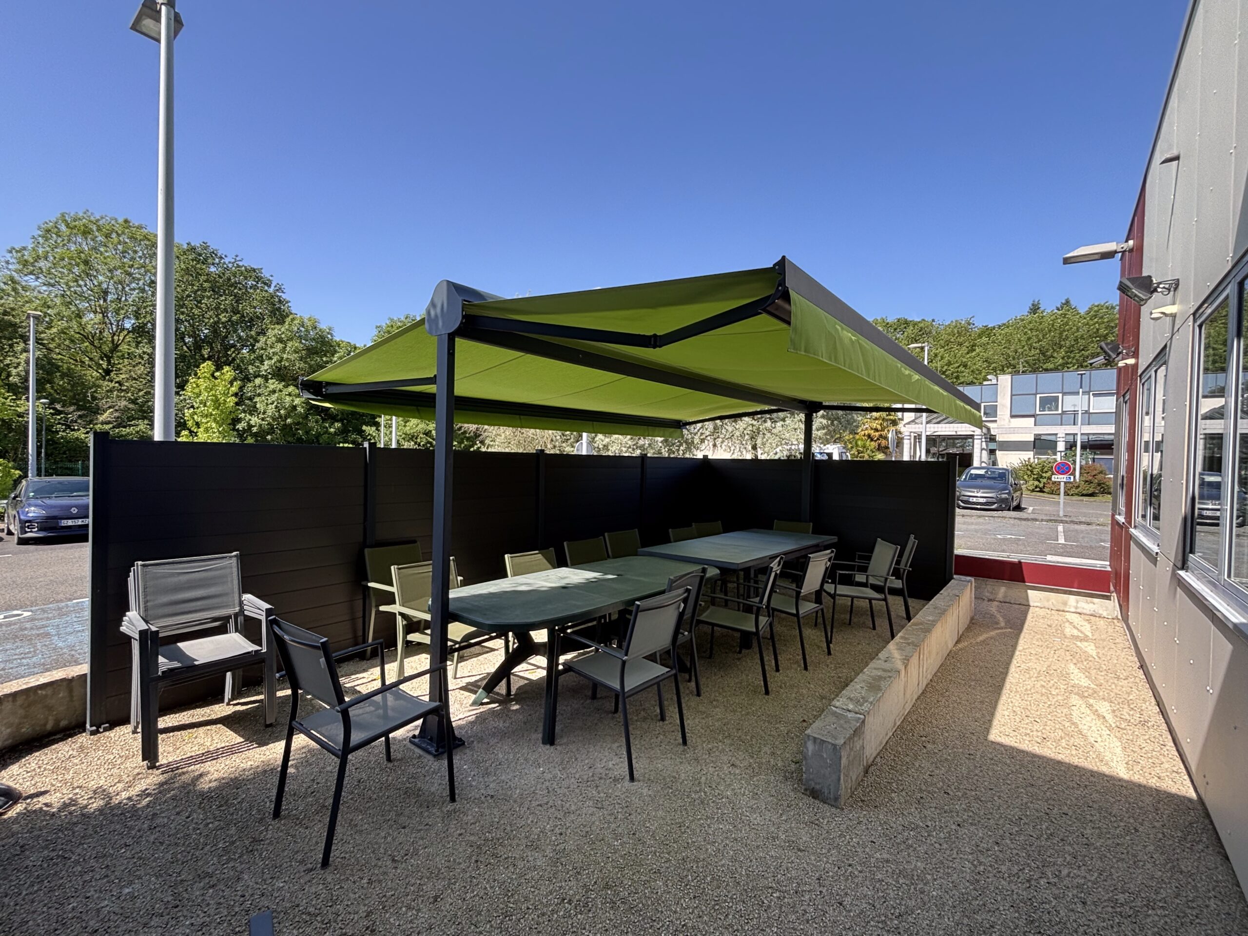 Store double pente avec une toile verte sur un terrasse d'une entreprise